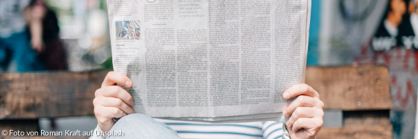 Ein Mann sitzt auf einer Bank und liest Zeitung